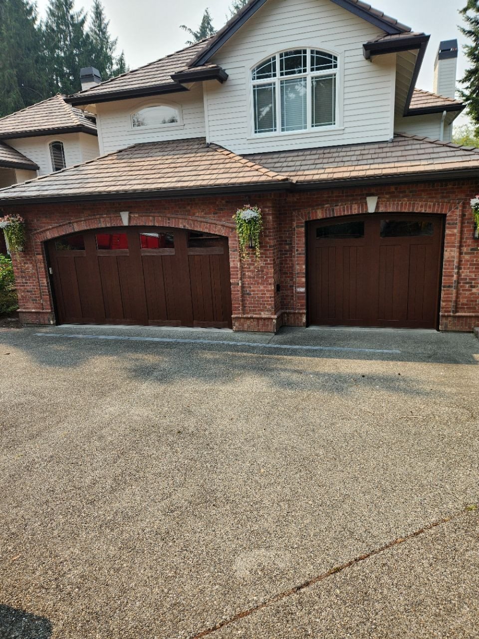 Two Clopay Canyon Ridge garage doors installed by The Doorman Service Co. on a brick home in the Puget Sound area